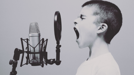 Boy singing loudly into microphone.