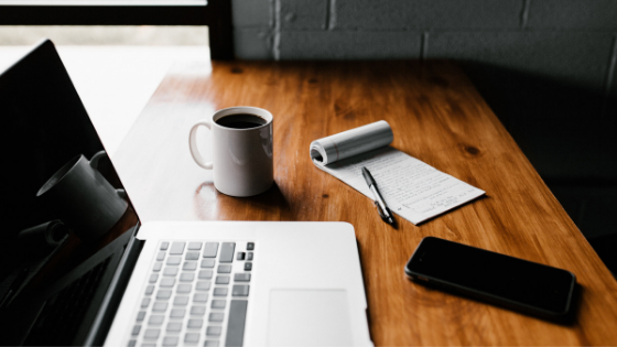 Picture of a laptop and notebook on a desk.